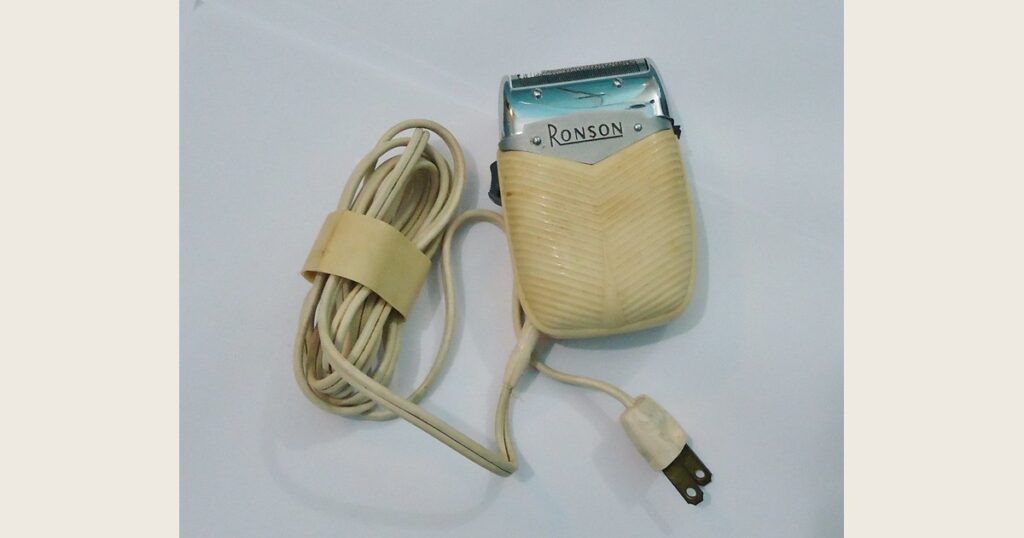 A vintage electric shaver against a plain background.