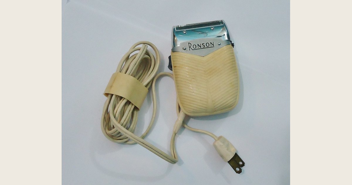 A vintage electric shaver against a plain background.