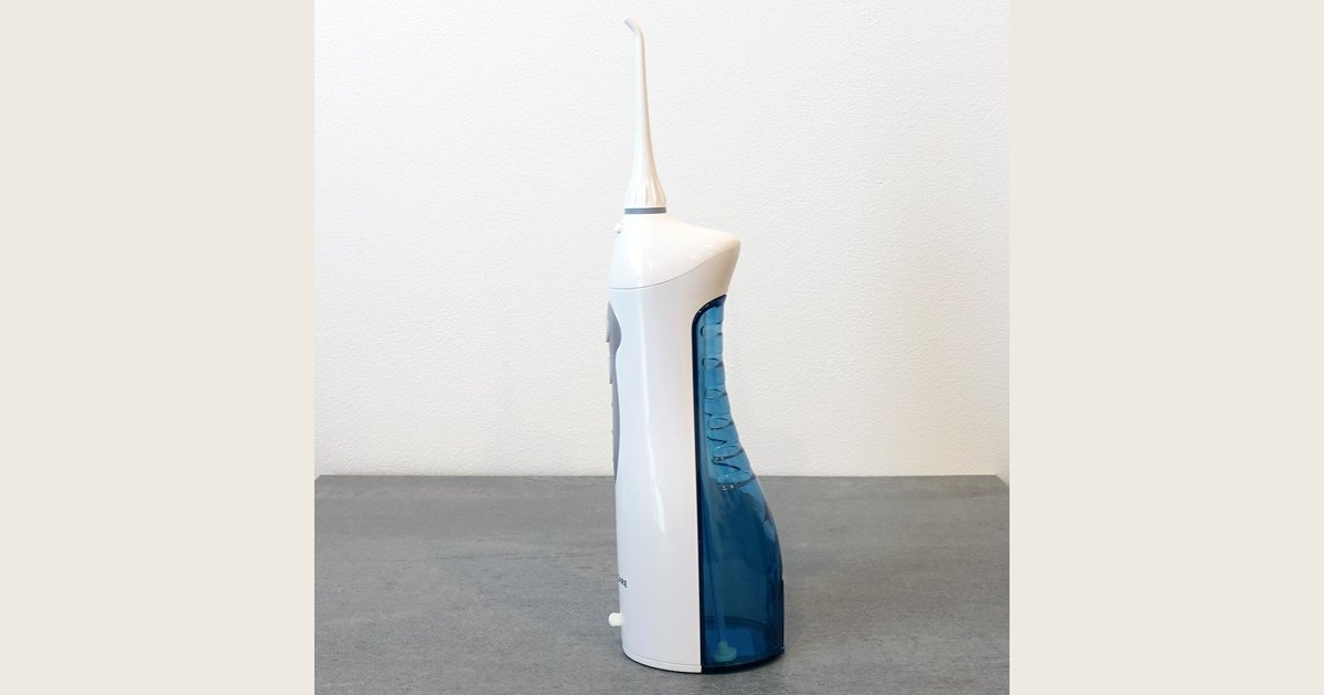 A white portable water flosser with a clear reservoir, gray controls, and a curved white tip.