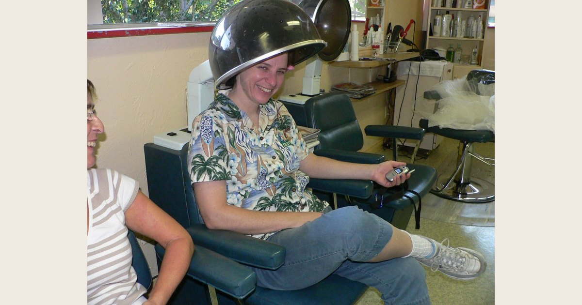 A client sits beneath a hooded dryer in a salon.